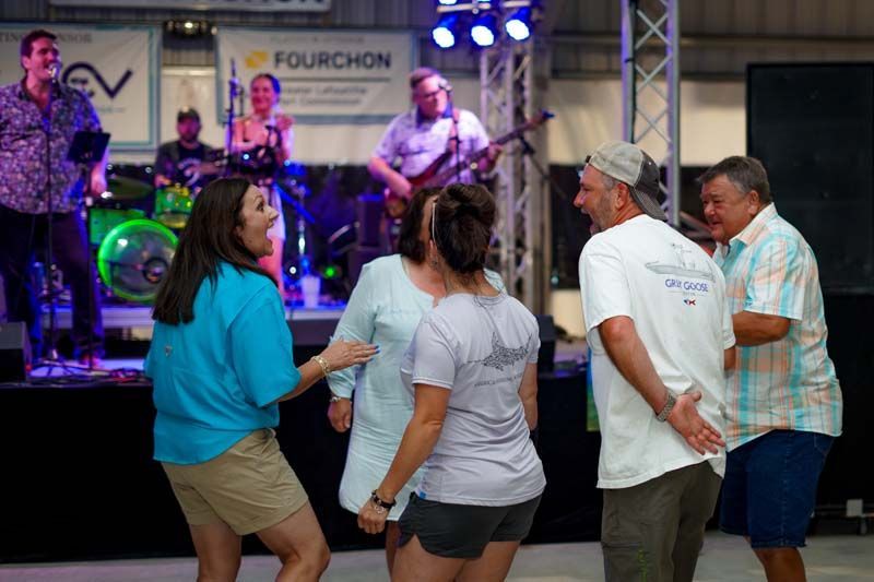 A group of people are dancing on a stage in front of a band.
