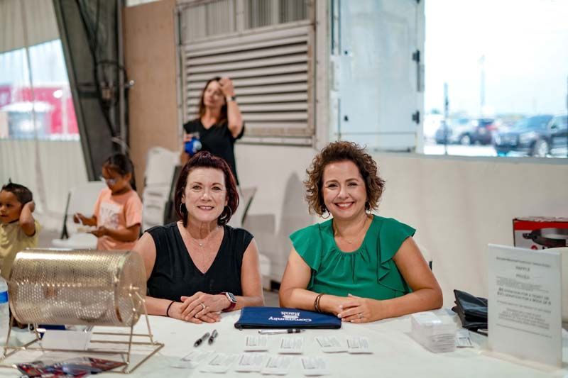 Two women are sitting at a table in front of a lottery machine.