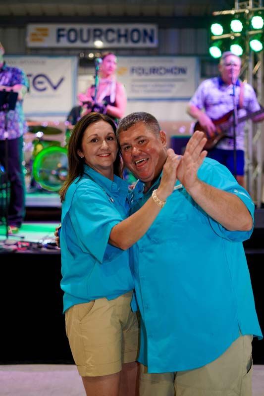 A man and a woman are posing for a picture in front of a sign that says fourchon