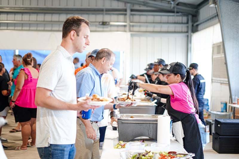 A group of people are standing around a table eating food.