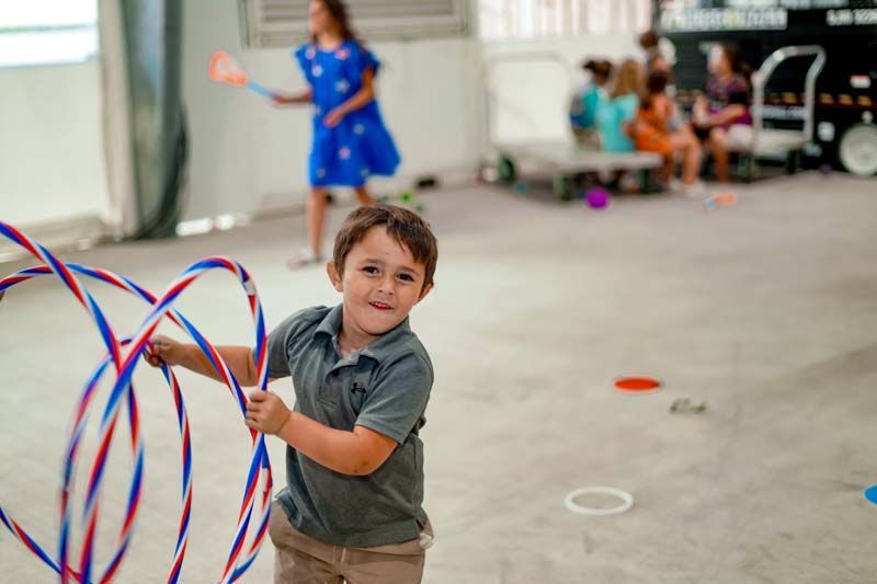 A young boy is holding a red , white and blue hula hoop.