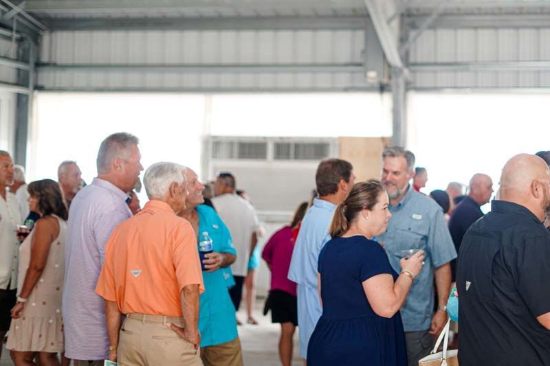 A group of people are standing in a room talking to each other.