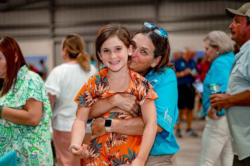 A woman is holding a little girl in her arms in a crowd of people.