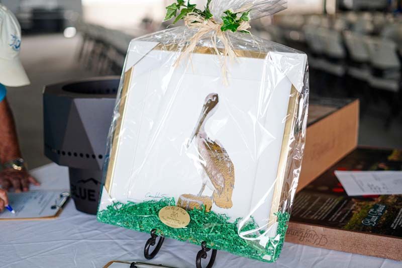 A picture of a pelican holding a golf club is wrapped in plastic and sitting on a table.