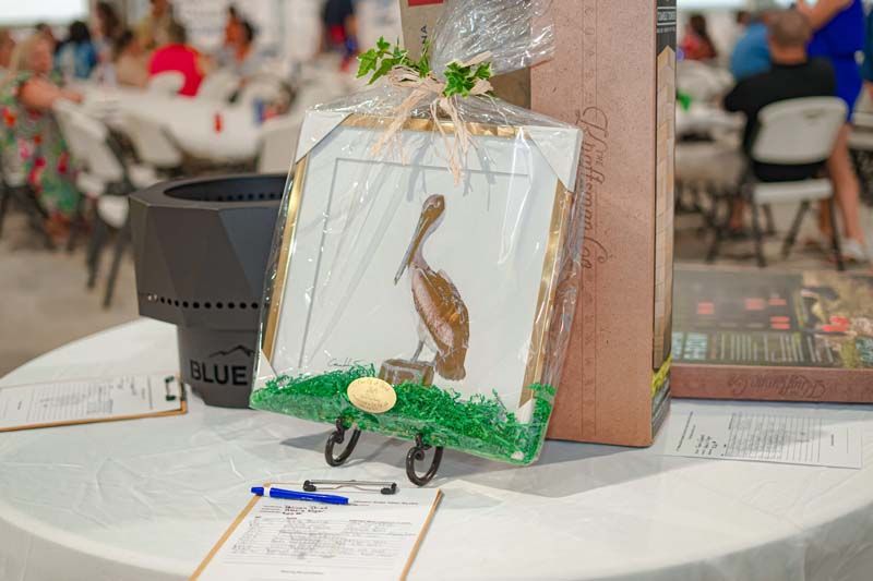 A painting of a bird is sitting on a table next to a clipboard.