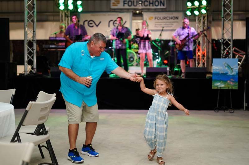 A man and a little girl are dancing in front of a band.