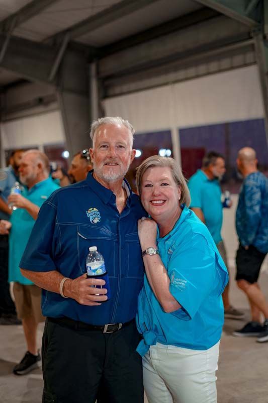 A man and a woman are posing for a picture while the man is holding a bottle of water.