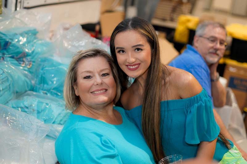 Two women are posing for a picture in front of a pile of plastic bags.