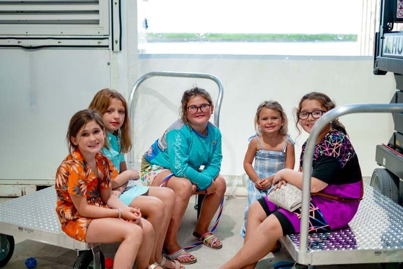 A group of young girls are sitting on a cart in a room.