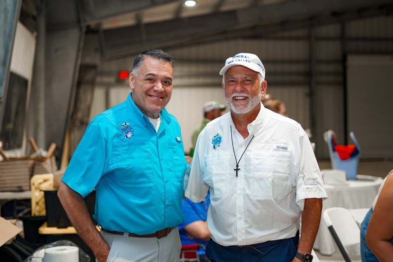 Two men are standing next to each other in a room and smiling.