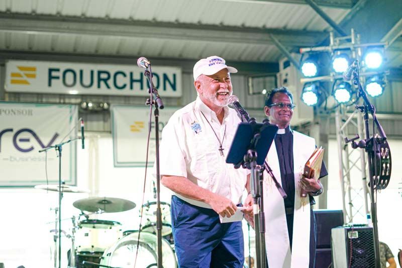 A man is standing in front of a sign that says fourchon