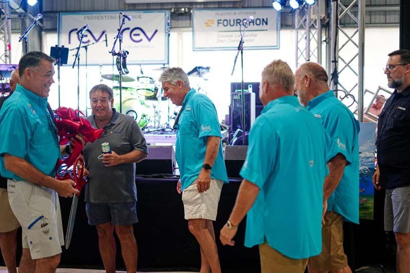 A group of men in blue shirts are standing in a room.