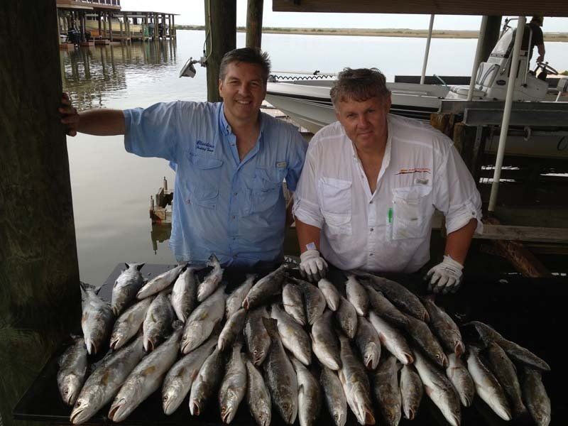 Two men standing next to a table full of fish
