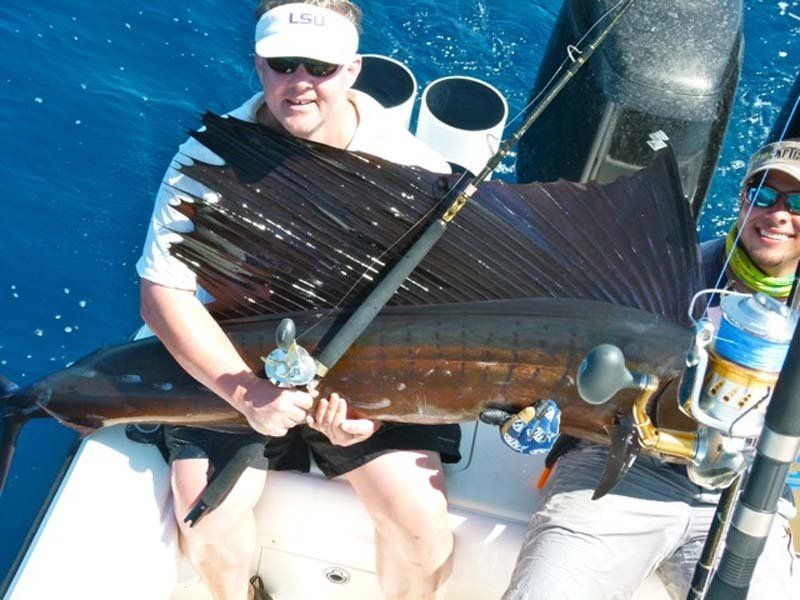 Two men on a boat holding a large sailfish
