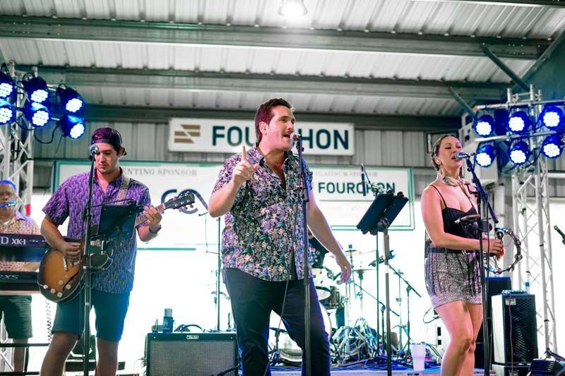 A group of people are standing on a stage playing instruments and singing into microphones.