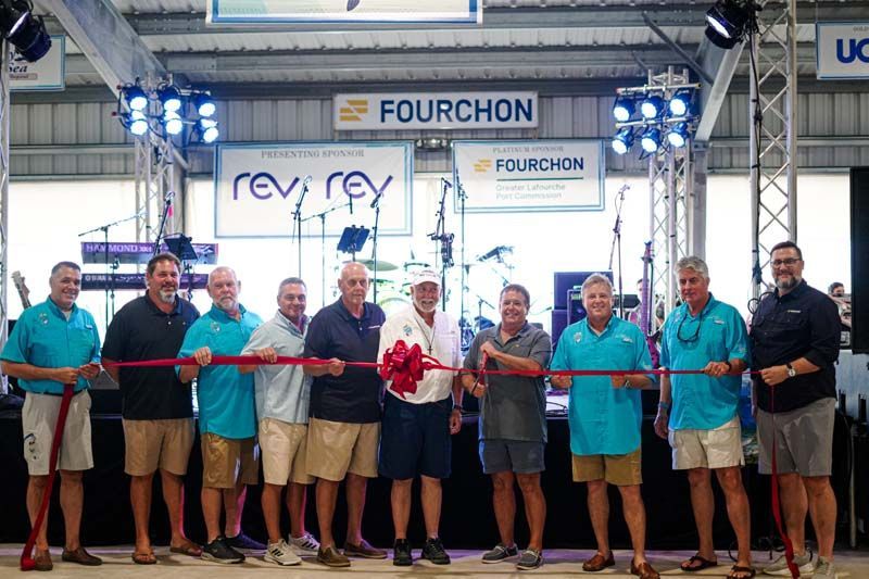 A group of men are standing next to each other holding a red ribbon.