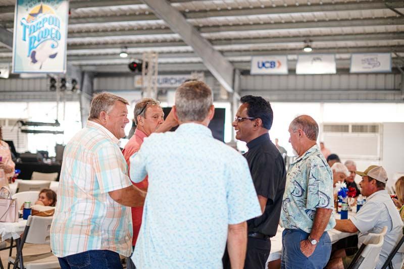 A group of men are standing in a room talking to each other.
