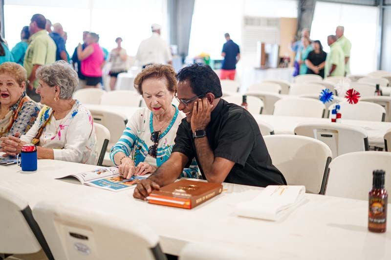 A man and a woman are sitting at a table looking at a book.