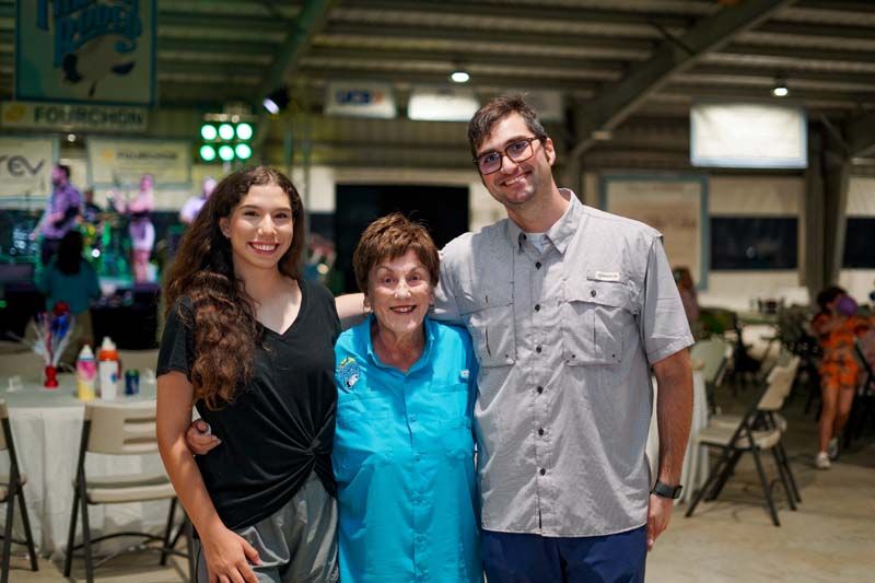 A man and two women are posing for a picture in a room.
