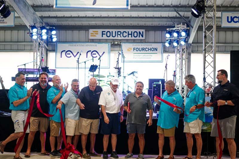 A group of men are standing in front of a sign that says fourchon