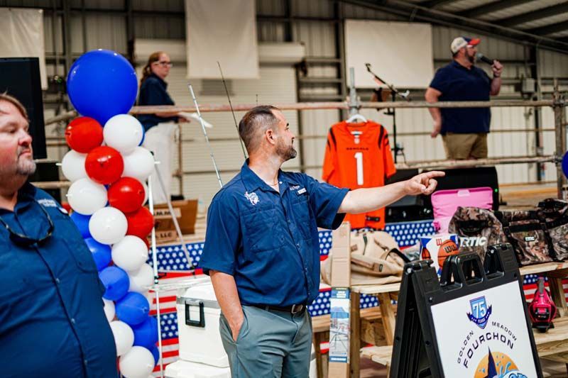 Two men are standing next to each other in a room with balloons and a sign.