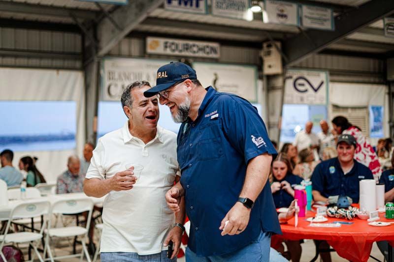 Two men are standing next to each other in a room talking to each other.