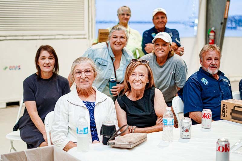 A group of people are posing for a picture while sitting at a table.