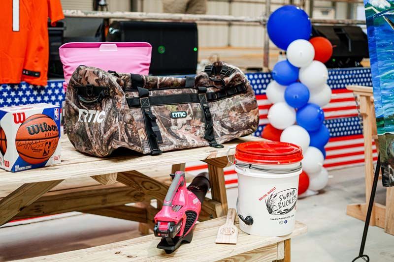 A picnic table with a bag , basketball , and bucket on it.