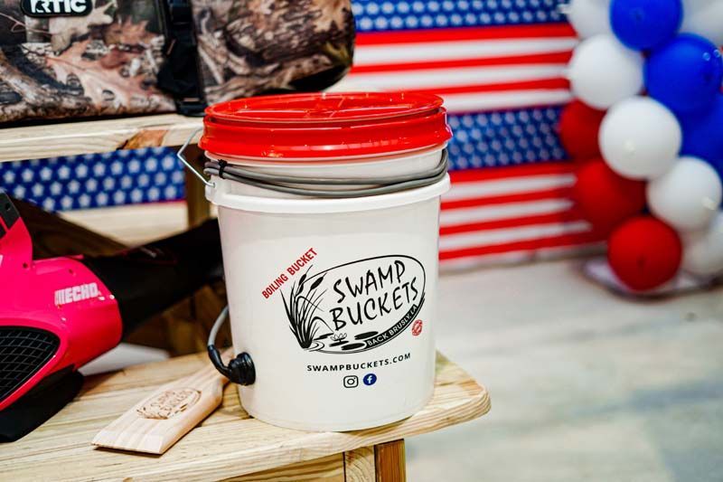 A white bucket with a red lid is sitting on a wooden table.