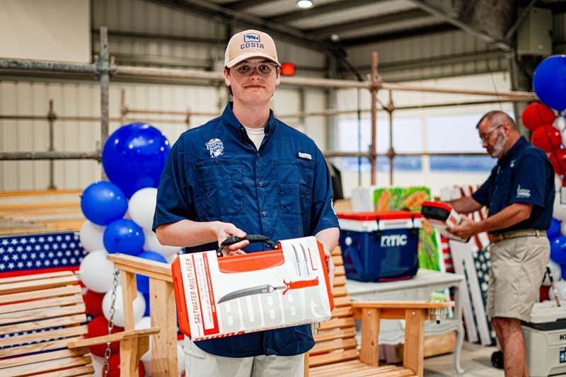 A man is holding a box in front of a wooden bench.