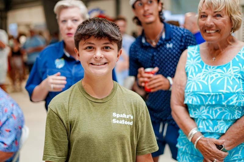A boy in a green shirt is standing in front of a group of people.
