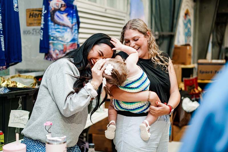 Two women are standing next to each other holding a baby.