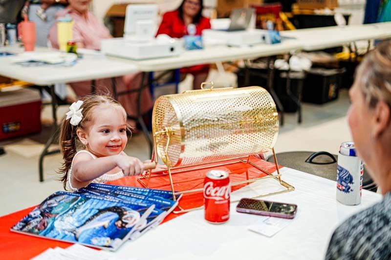 A little girl is sitting at a table playing a lottery game.