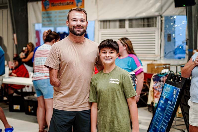 A man and a boy are posing for a picture in a crowded room.