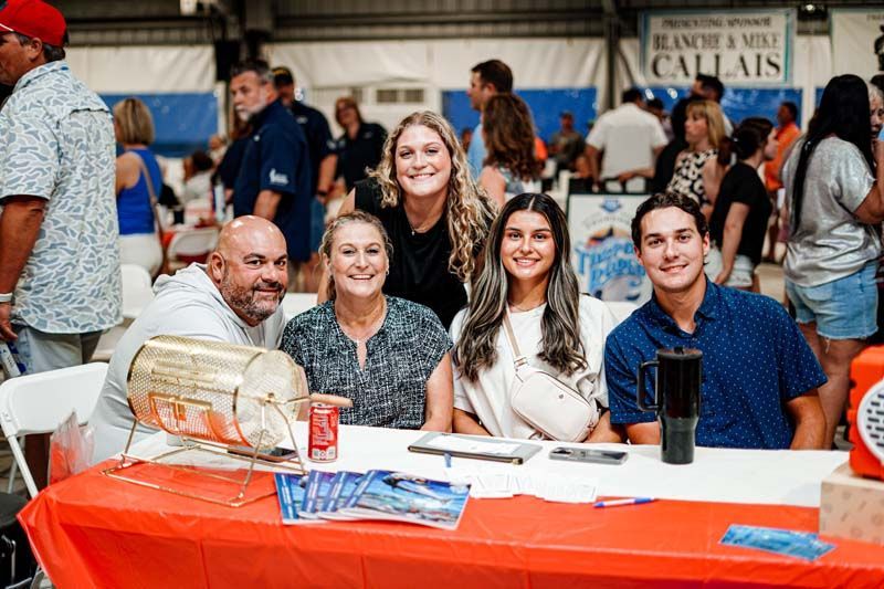 A group of people are sitting at a table posing for a picture.