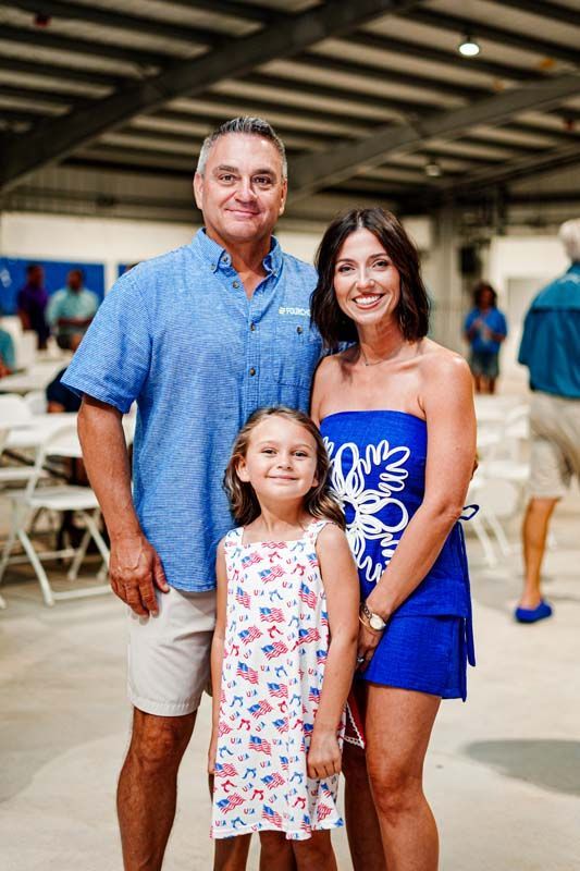 A man , a woman and a little girl are posing for a picture.