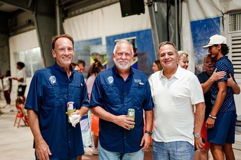 Three men are standing next to each other in a room.