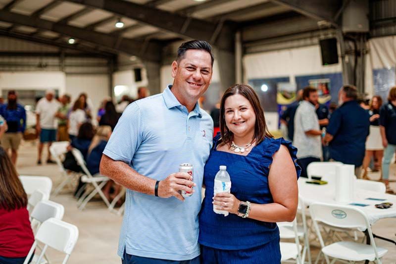 A man and a woman are standing next to each other in a room holding bottles of water.