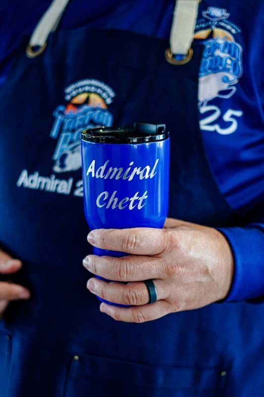 A person is holding a blue cup with the name admiral written on it.