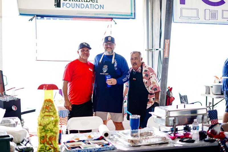 Three men are standing next to each other in front of a table.