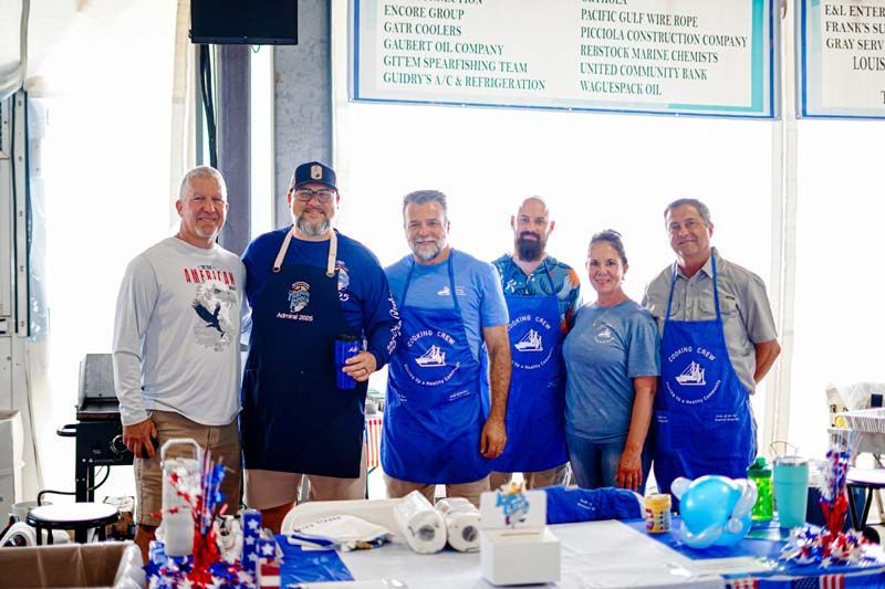 A group of people wearing aprons are standing around a table.
