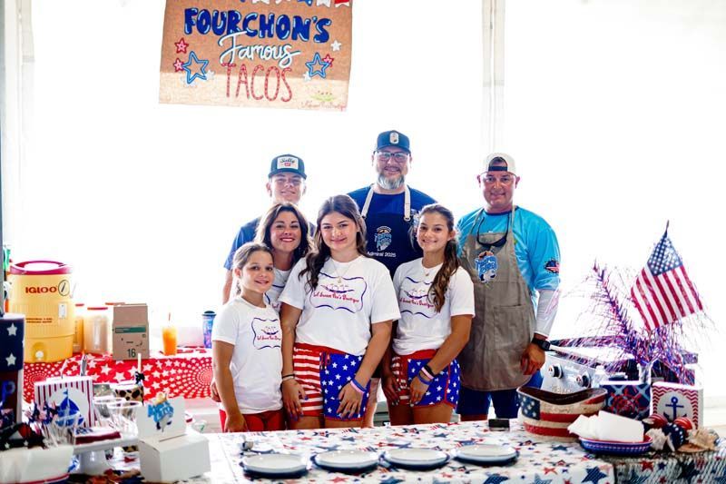 A group of people are posing for a picture in front of a taco stand.