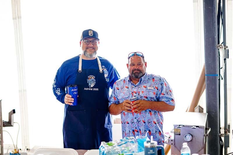 Two men are standing next to each other in front of a table.