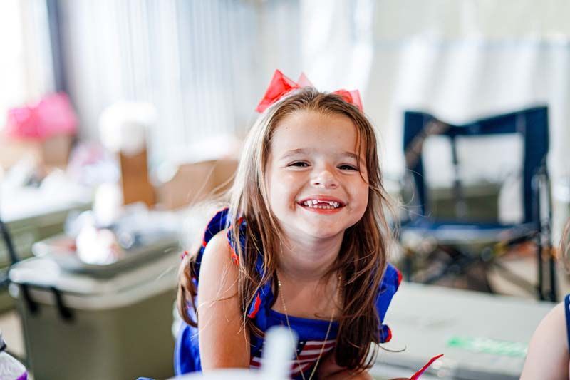 A little girl is smiling for the camera while sitting at a table.