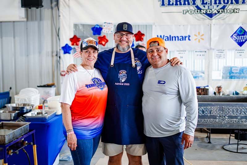 Three people are posing for a picture in front of a walmart sign.