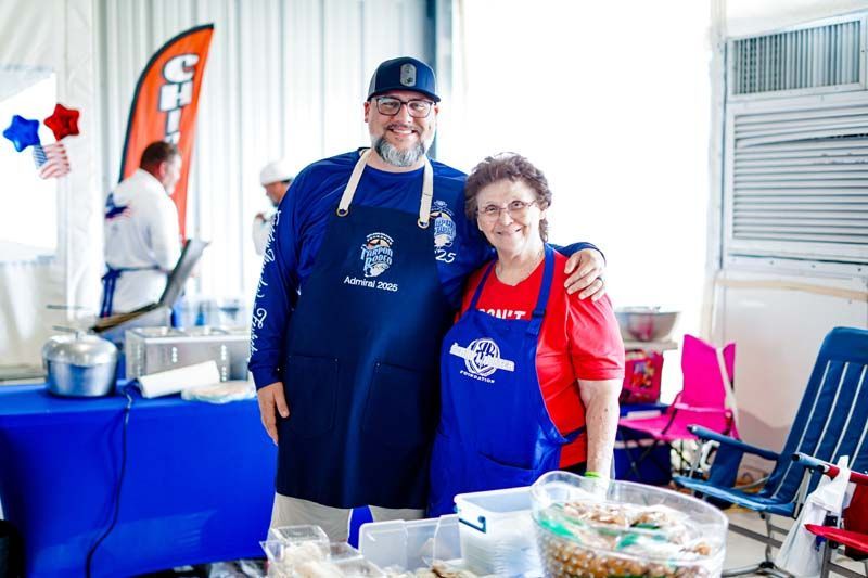 A man and a woman are posing for a picture in front of a table.