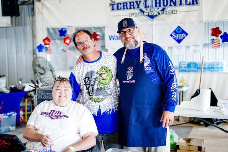 Three people are posing for a picture in front of a banner that says terry l. hunter
