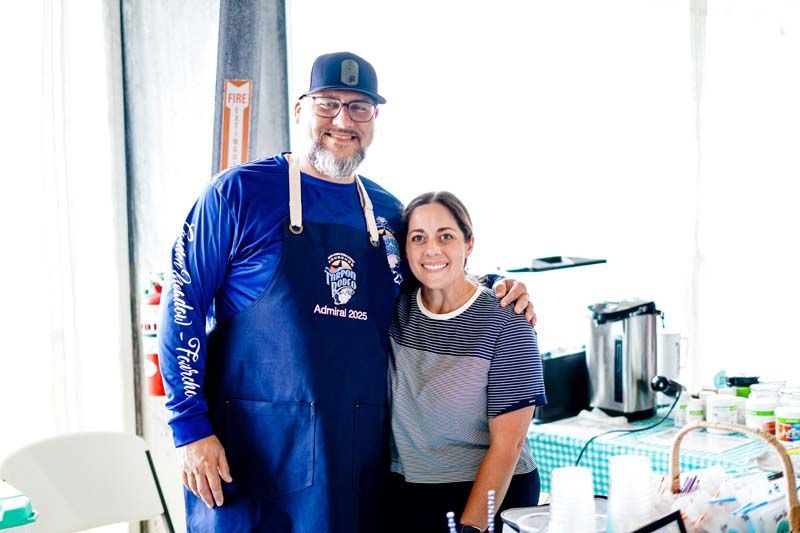 A man and a woman are posing for a picture in a kitchen.