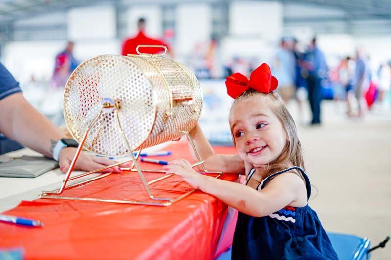 A little girl is sitting at a table playing a lottery machine.