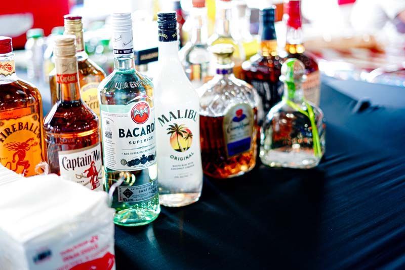 A table topped with bottles of alcohol including bacardi malibu and captain morgan